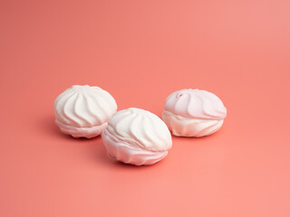 White and pink meringue cookies on a pink background. Meringue cookies close-up.
