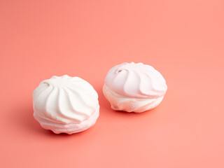 White and pink meringue cookies on a pink background. Meringue cookies close-up.