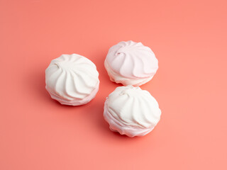 White and pink meringue cookies on a pink background. Meringue cookies close-up.