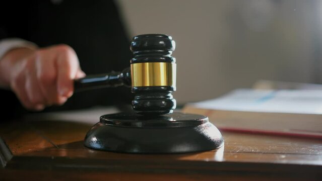 Judge's hand with wooden judge gavel and American flag background, close up shot