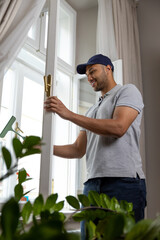 Bearded man washing dusty window in apartment.