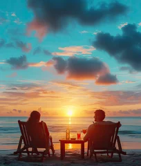  happy couple on beach chairs with a side table with cocktails enjoy luxurious sunset on the beach during summer vacations. © Tjeerd