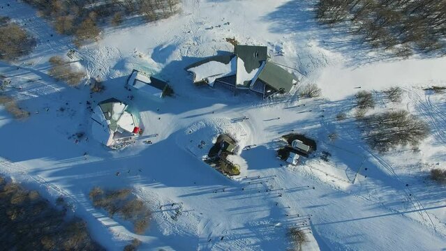 Mountain base with ropeway and crowd of people at winter sunny day. Aerial view