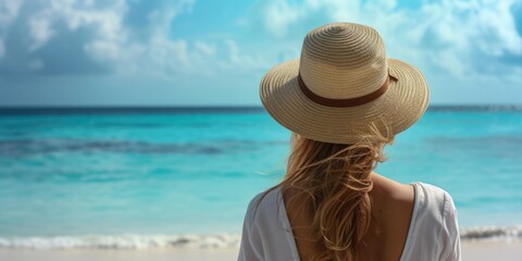 A woman wearing a hat gazes at the vastness of the ocean. Suitable for travel or relaxation concepts
