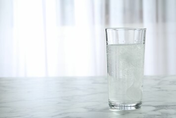 Glass of water with effervescent tablet on marble table indoors, space for text