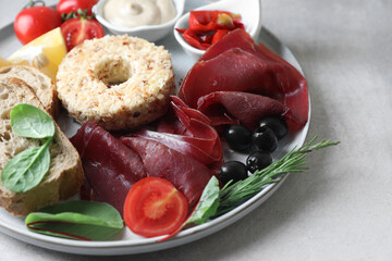 Delicious bresaola and other ingredients for sandwich on light grey table, closeup