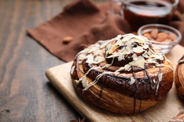 Sweet bun. Delicious roll with toppings and nuts on wooden table, closeup. Space for text