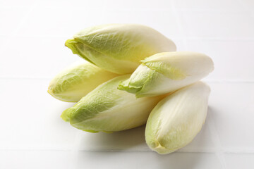 Fresh raw Belgian endives (chicory) on white tiled table