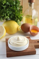 Fresh mayonnaise sauce in bowl on white wooden table