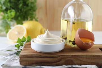 Fresh mayonnaise sauce in bowl and ingredients on table
