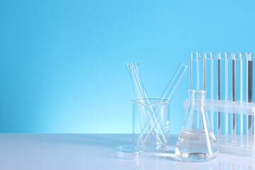 Laboratory analysis. Different glassware on table against light blue background, space for text