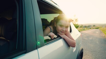 child girl face looks smiling from car out window, summer vacation mood, car driving time, summer...