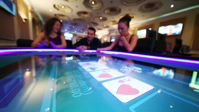 Cards on electronic screen of poker table and three people