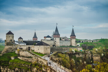 Fototapeta premium Old Kamianets-Podilskyi Castle under a cloudy grey sky. The fortress located among the picturesque nature in the historic city of Kamianets-Podilskyi, Ukraine