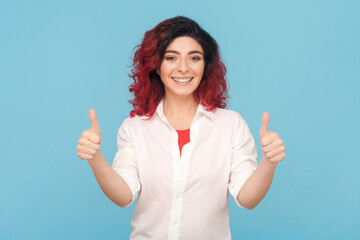 Thumbs up, excellent job. Portrait of enthusiastic woman with fancy red hair smiling and showing...