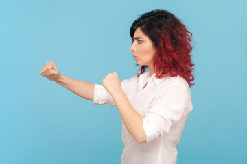 Side view portrait of strict arguing woman with fancy red hair standing with clenched fists,...