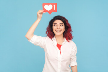 Portrait of joyful cheerful woman with fancy red hair holding blogger heart above head,...