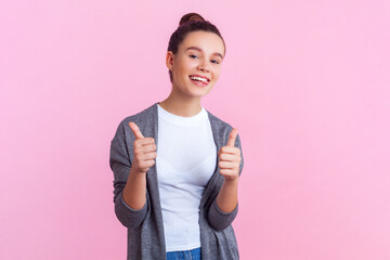 Portrait of satisfied delighted teenage girl with bun hairstyle in casual clothes standing showing...