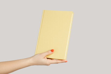 Closeup of woman hand showing textbook or organizer with empty cover. Indoor studio shot isolated on gray background.