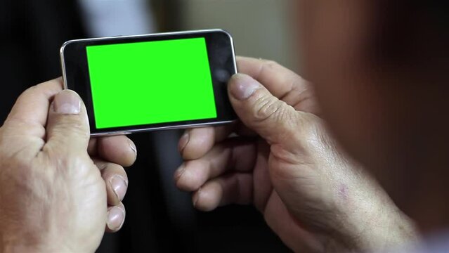 An Unrecognizable Senior Man Using A Cellphone Green Screen. Close Up. Zoom In. You can replace green screen with the footage or picture you want with “Keying” effect in After Effects.