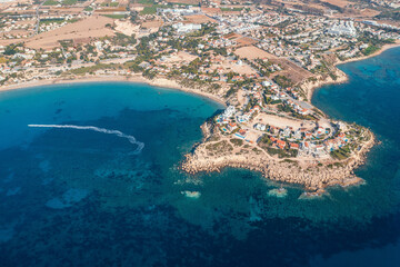 Aerial top down view of picturesque village nestled by Cyprus coastline, with azure waters and...