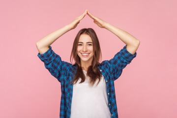 Portrait of smiling beautiful brown haired woman standing with raised arms making roof gesture...