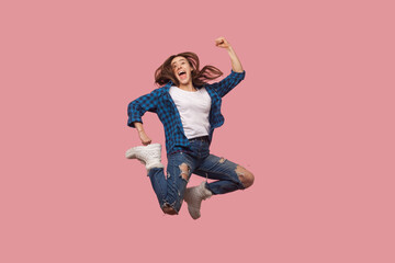Full length portrait of extremely happy brown haired woman jumping with clenched fists celebrating...