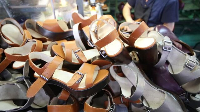 New female shoes in workshop, hands of workers in factory