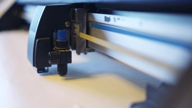 Cutting machine cuts sticker on white adhesive paper