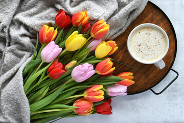 Colorful bouquet of tulips and a cup of coffee latte on a tray - cozy hygge background © MargJohnsonVA