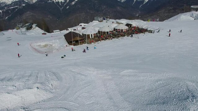 Snowcat works near ski track with people and chairlift Tale at sunny day.