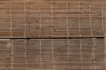 Stacks of boards, board flooring in a sawmill. Warehouse for cutting boards in a sawmill outdoors. Stack of wooden blanks construction material wood timber. Industry.