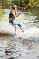 Fototapeta premium Wakeboarding and water sports activity. Man wakeboarding on a lake. Man water skiing in summer