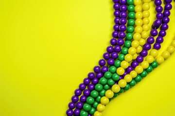 Purple and green beads on yellow background with copy space for advertiser