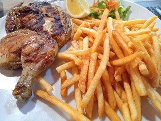 dish with half a grilled chicken and french fries