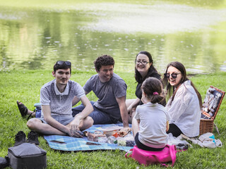 A large and friendly family with children on a picnic in the park.