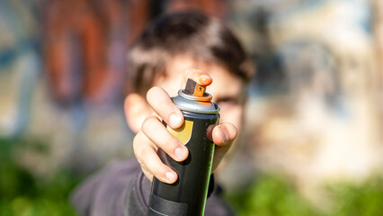 Child painting with aerosol spray pointing at the camera with the background out of focus. Detail...