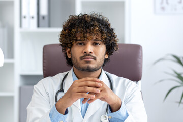 A young Hindu doctor exudes professionalism and confidence as he sits in a medical office with a...