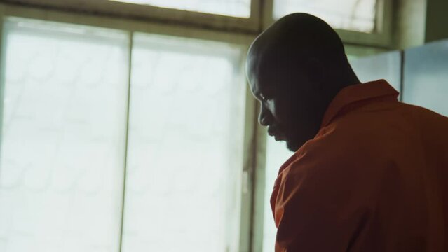 Tilt up handheld shot of African American inmate mopping floor while serving time in prison