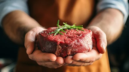 Tuinposter Experienced butcher in white apron skillfully holding a large, succulent, and marbled raw beef steak © Ilja