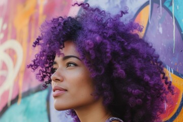 Young woman with violet curly hair looking at a vibrant street mural