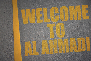 asphalt road with text welcome to Al Ahmadi near yellow line.