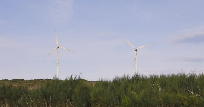 Wind turbines spinning on blue clear background producing electricity