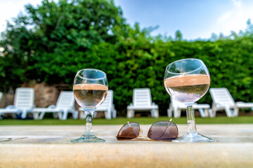 glasses of white wine beside a swimming pool
