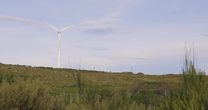 Wind turbines spinning on blue clear background producing electricity