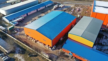 Transport and logistics center near a large city, megalopolis. Product storage warehouses for distribution to retail chains. Huge hangar with blue roof and orange walls for storage of goods.