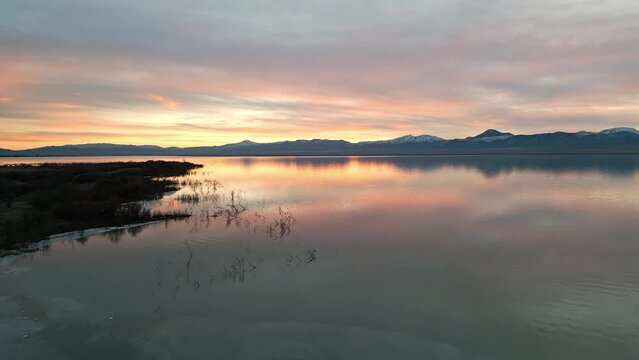 Aerial view over Utah Lake during sunset moving over thin ice on the water.