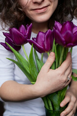 Obraz na płótnie Canvas Purple tulips in hands natural on white t-shirt spring flowers warm background