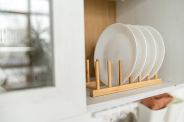 white plates are stacked on the shelf of the kitchen cabinet