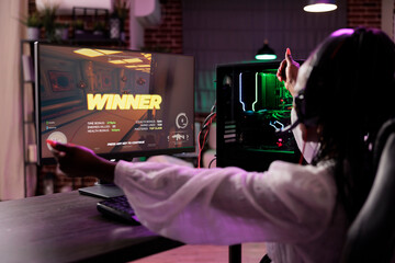 Cheerful gamer celebrating winning online multiplayer spaceship videogame tourney, defeating...